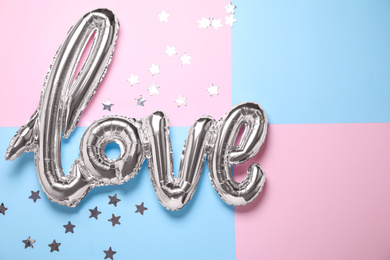 Foil balloon in shape of word LOVE on color background, above view