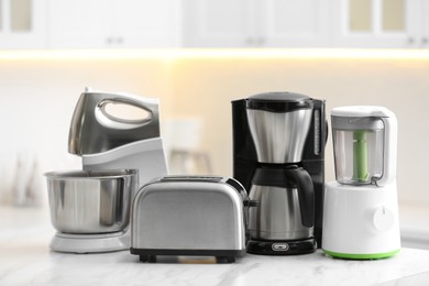 Photo of Modern toaster and other cooking appliances on table in kitchen