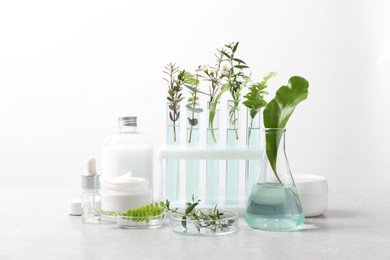 Photo of Natural ingredients and laboratory glassware for organic cosmetic product on white table