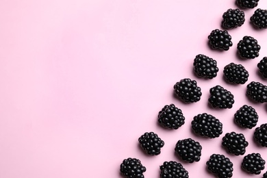 Photo of Tasty ripe blackberries on light pink background, flat lay. Space for text