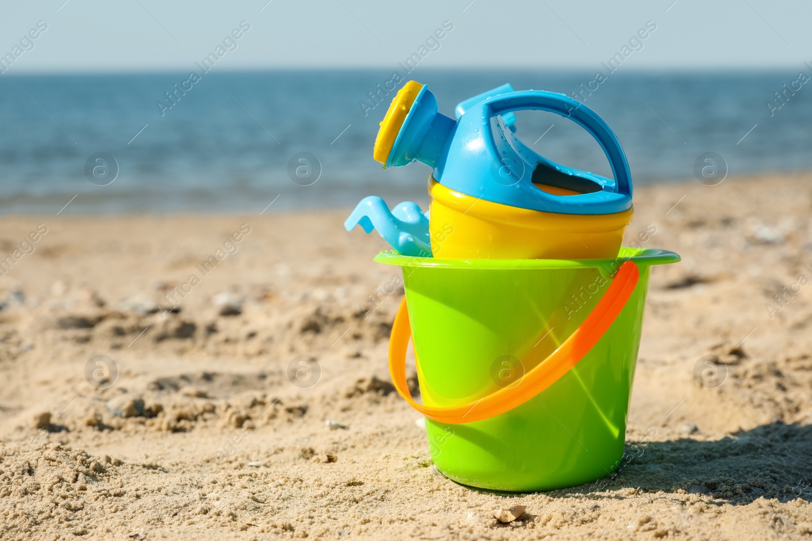 Photo of Different child plastic toys on sandy beach. Space for text