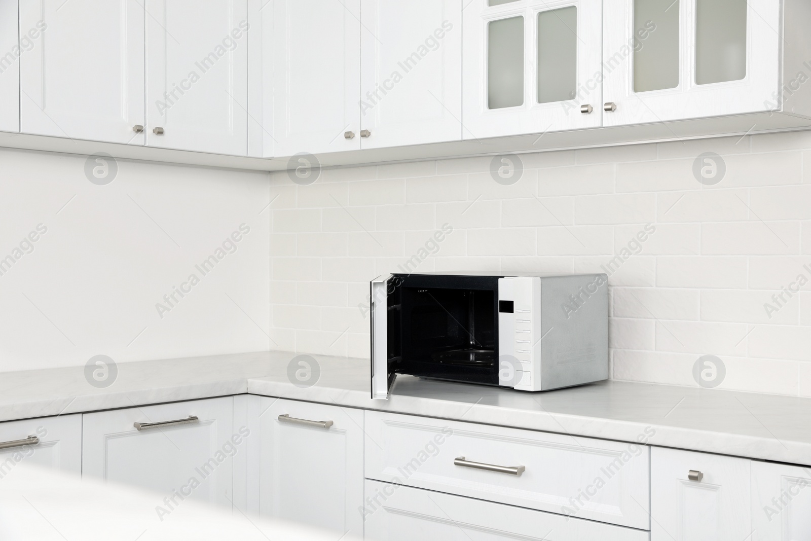 Photo of Modern microwave oven on countertop in kitchen