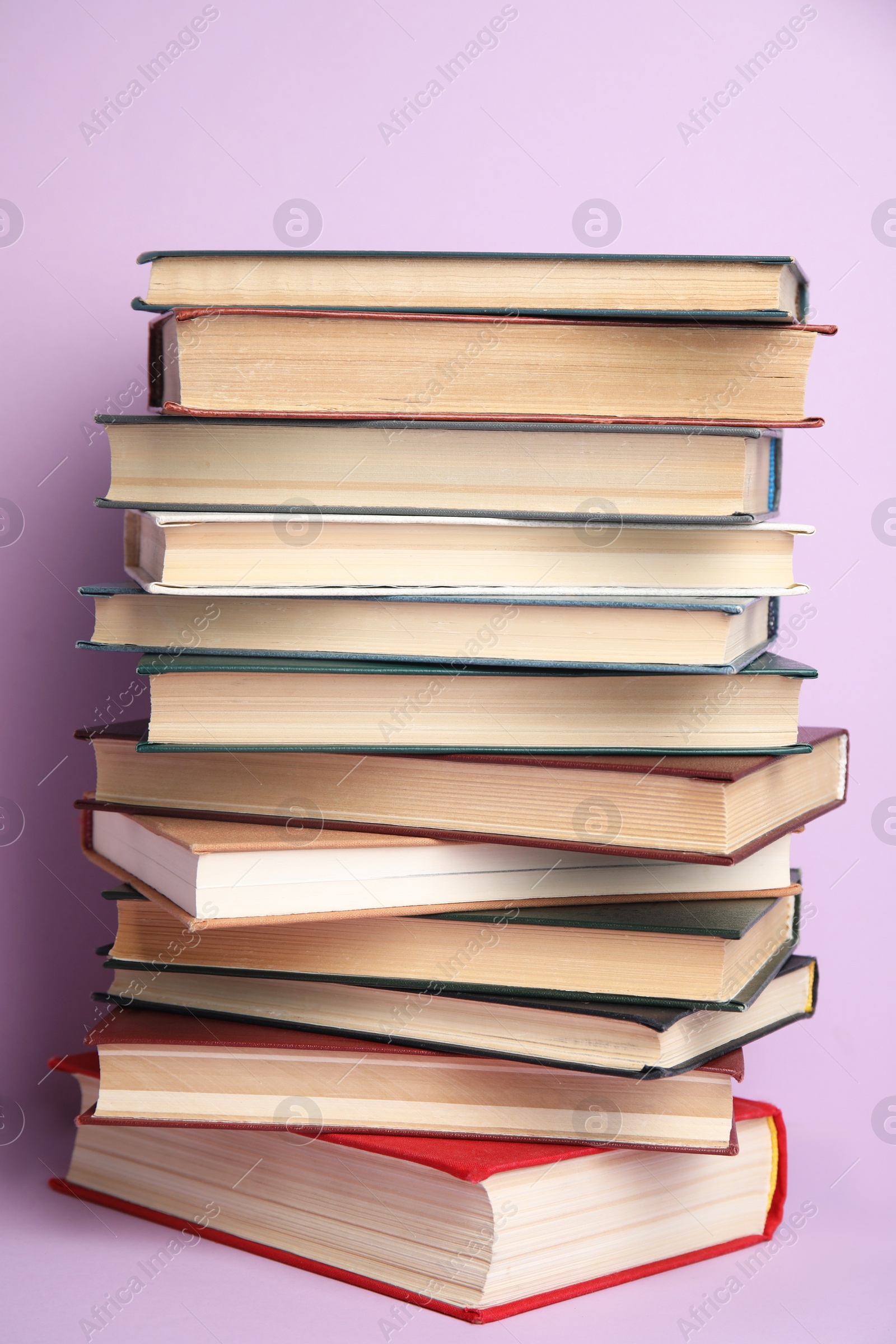 Photo of Stack of different hardcover books on violet background