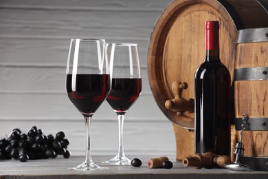 Photo of Delicious wine, wooden barrels and ripe grapes on light grey table