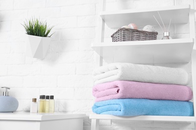 Stack of fresh towels on shelf in bathroom. Space for text