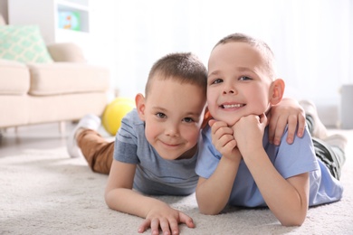 Portrait of cute twin brothers on floor in living room