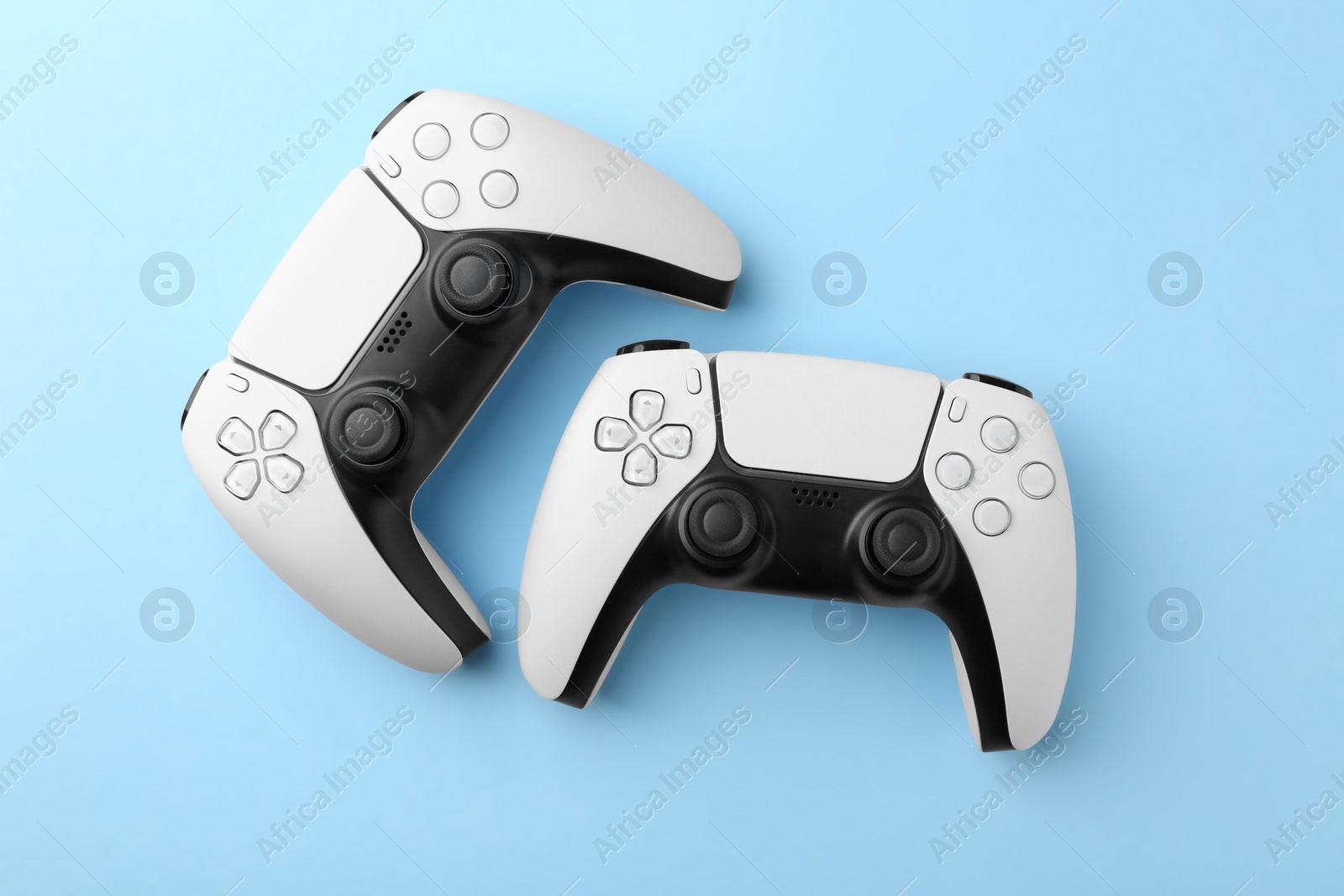 Photo of Wireless game controllers on light blue background, flat lay