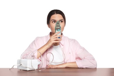 Photo of Young woman using nebulizer at wooden table on white background