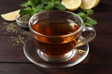 Photo of Glass cup of freshly brewed tea on wooden table, closeup