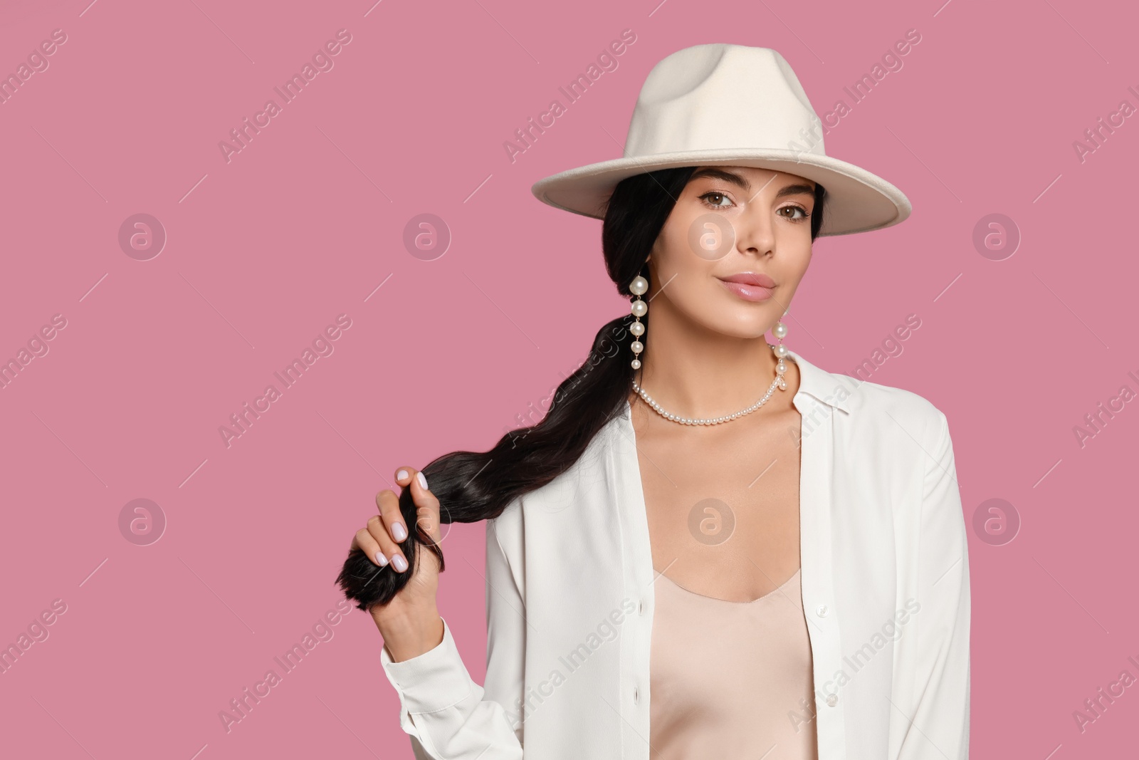 Photo of Young woman wearing elegant pearl jewelry on pink background, space for text