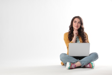 Photo of Pensive young woman sitting with laptop on white background