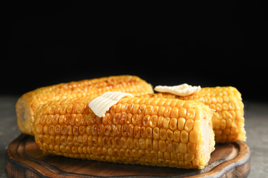 Delicious grilled corn with butter on wooden board, closeup
