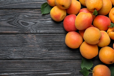 Many fresh ripe apricots on black wooden table, flat lay. Space for text