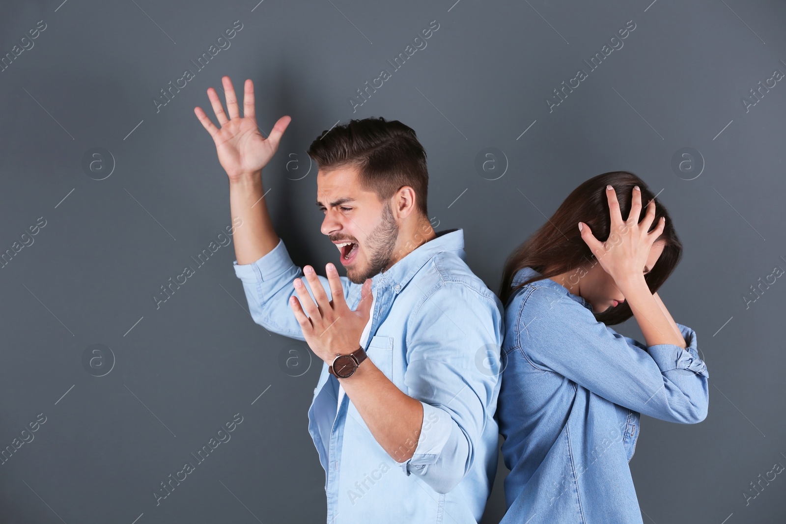 Photo of Young couple having argument on grey background. Relationship problems