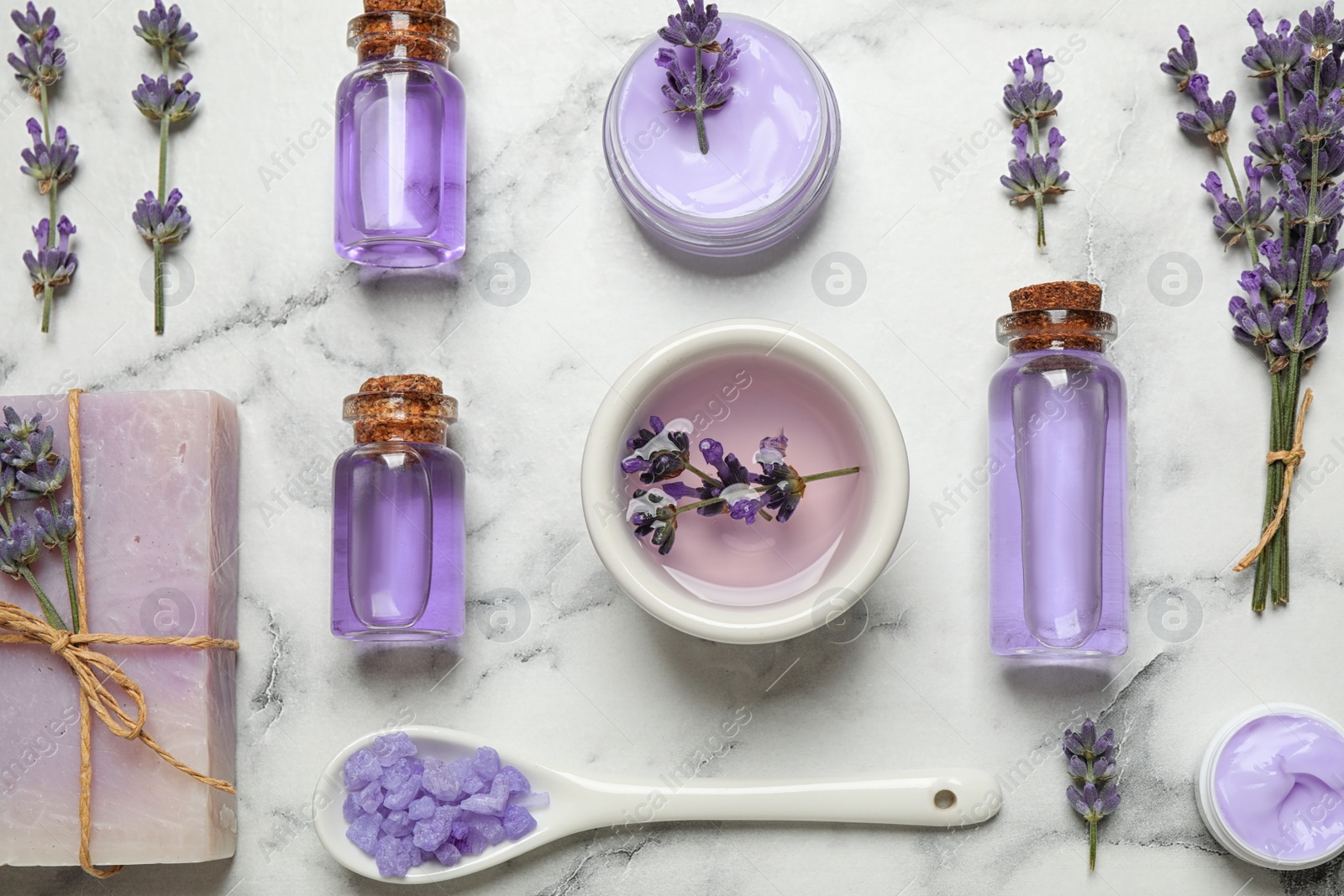 Photo of Cosmetic products and lavender flowers on white marble table, flat lay