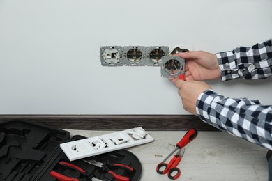 Electrician with screwdriver repairing power sockets indoors, closeup