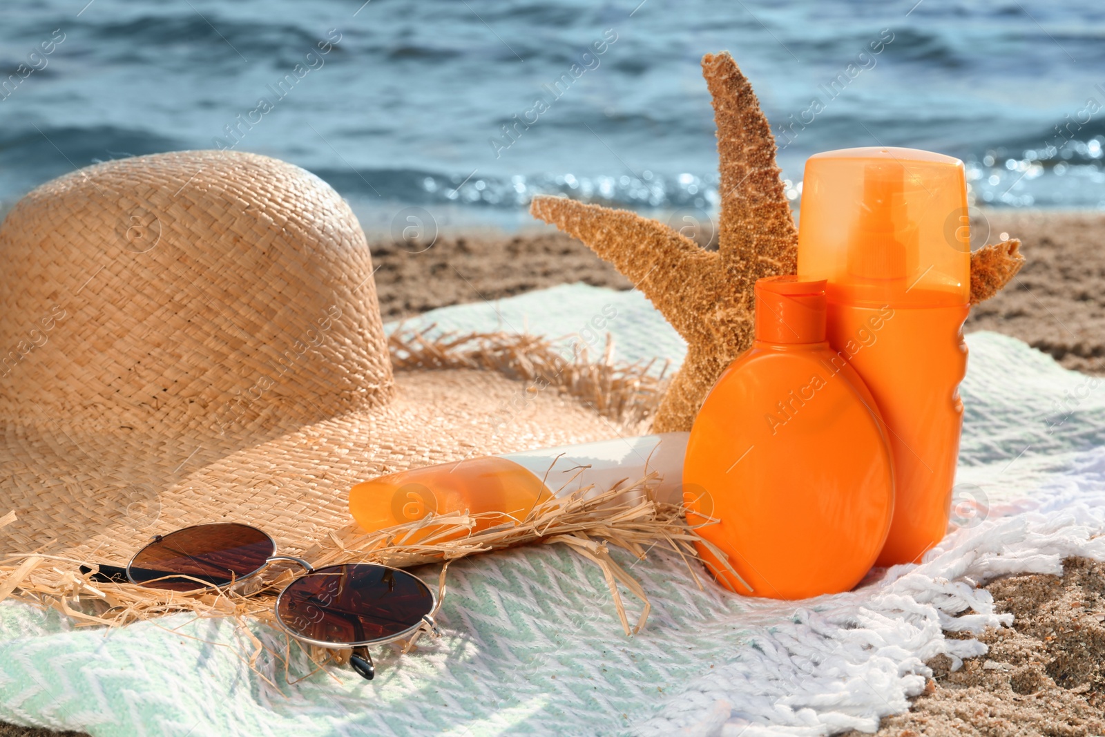 Photo of Sun protection products and beach accessories on blanket near sea