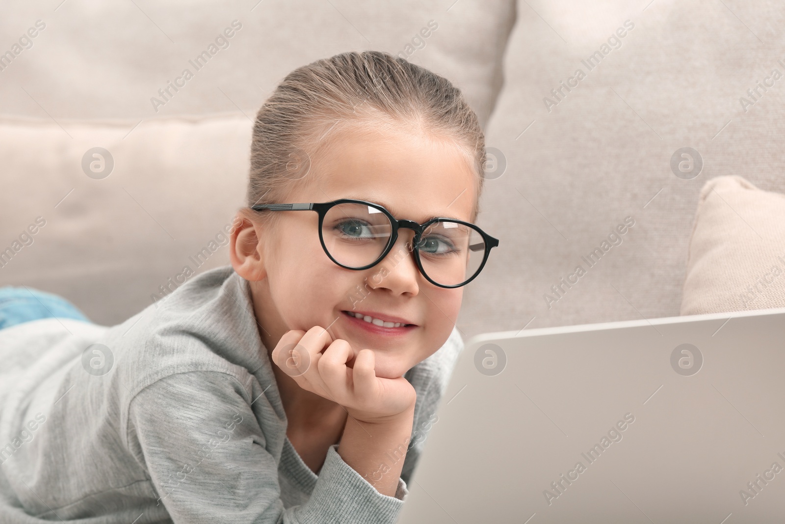 Photo of Portrait of little girl wearing glasses with laptop on sofa