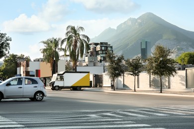 Photo of Picturesque view of city street with cars on road near beautiful mountains