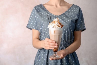 Photo of Woman holding glass with delicious milk shake on light background