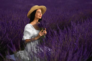 Photo of Beautiful young woman with bouquet sitting in lavender field