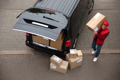 Courier with parcels near delivery van outdoors, above view