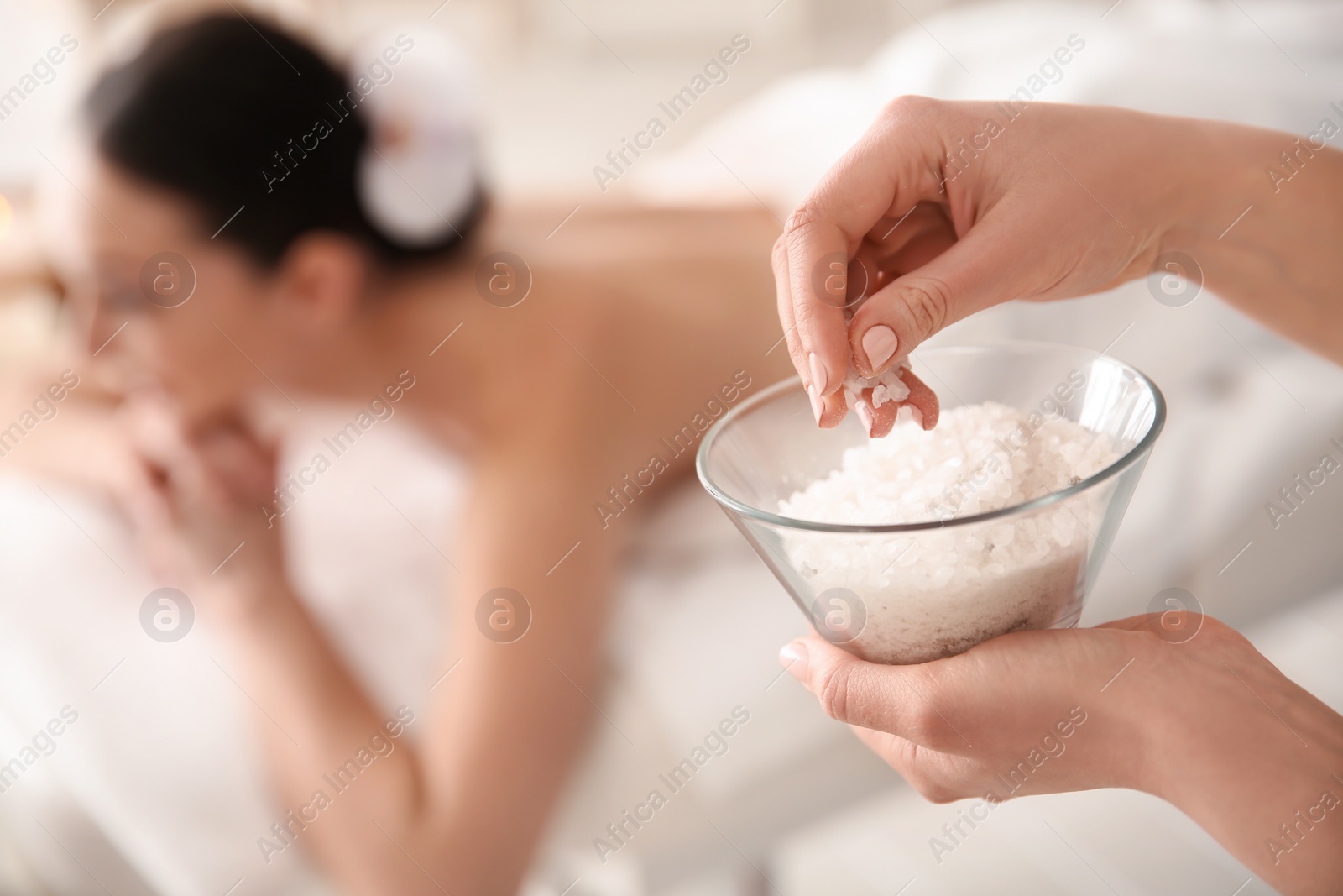 Photo of Cosmetologist holding bowl with body scrub in spa salon