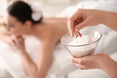 Photo of Cosmetologist holding bowl with body scrub in spa salon