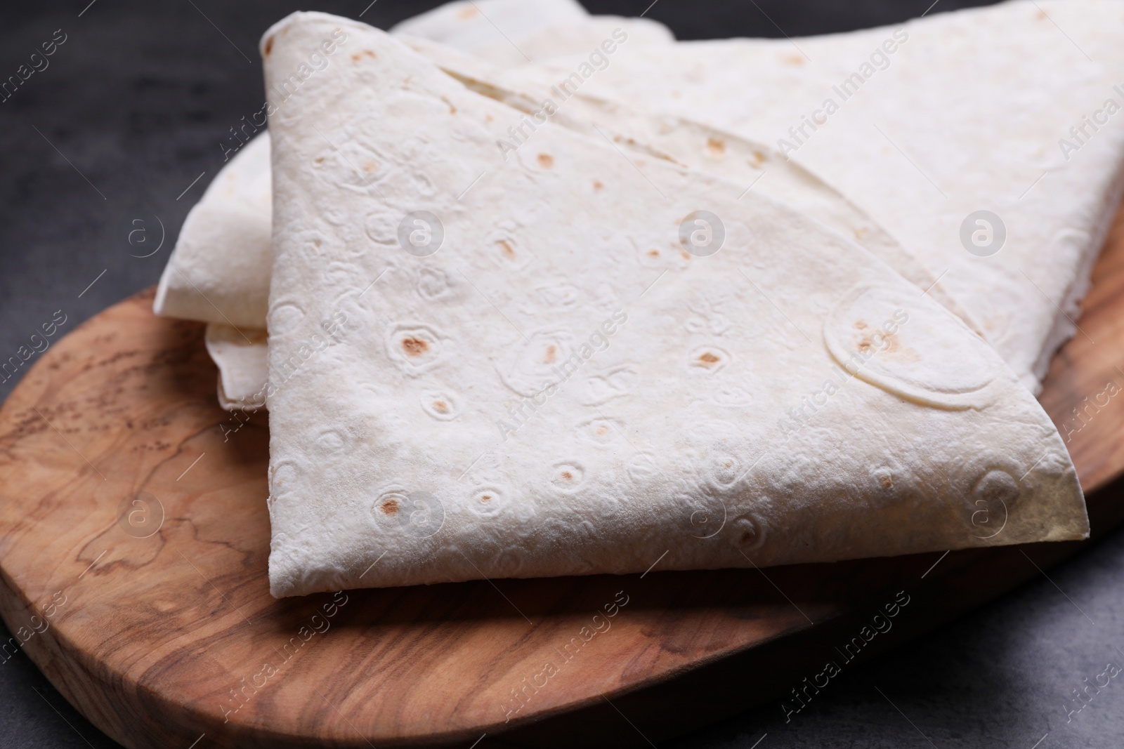 Photo of Delicious folded Armenian lavash on dark table, closeup