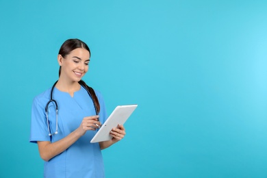 Photo of Portrait of medical assistant with stethoscope and tablet on color background. Space for text