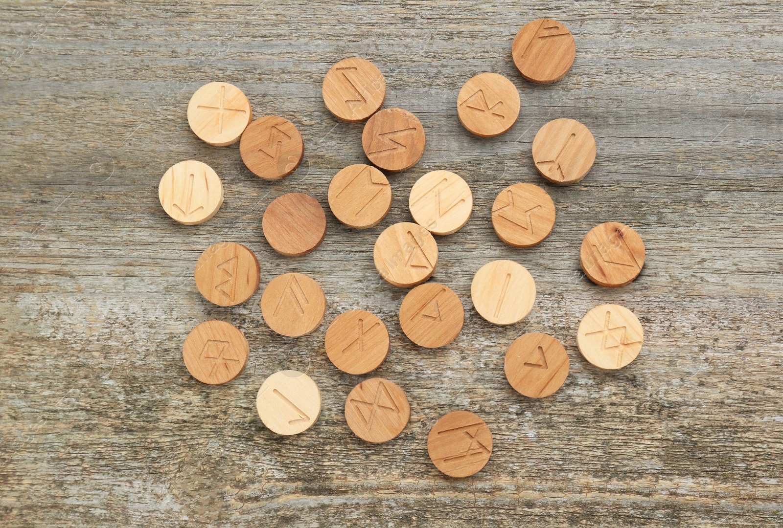 Photo of Runes with different symbols on wooden table, flat lay