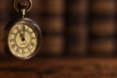 Photo of Pocket clock hanging on blurred background, closeup. Space for text