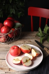 Photo of Fresh red apples, leaves and knife on wooden table
