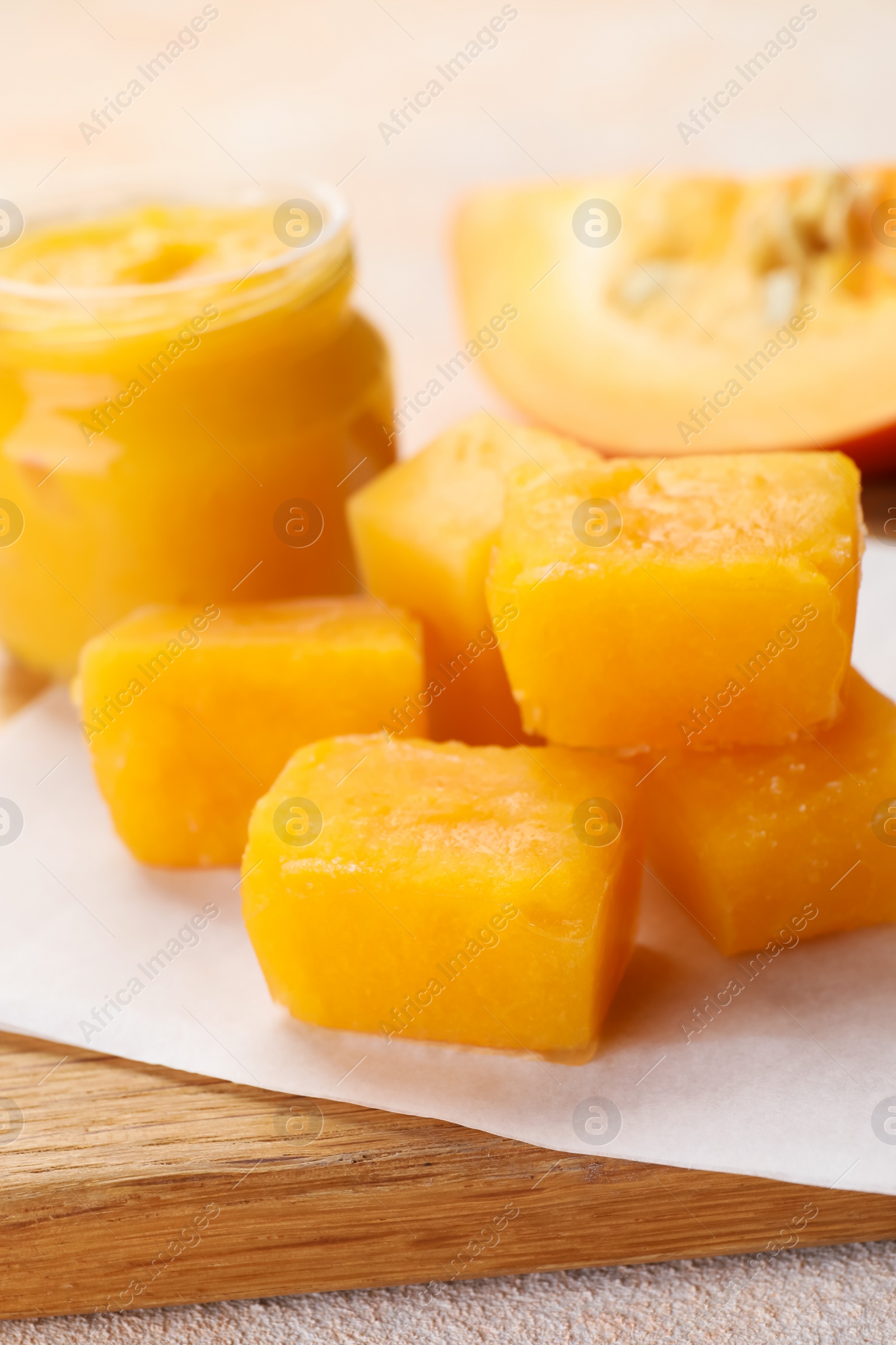 Photo of Frozen pumpkin puree cubes with ingredient on wooden board, closeup