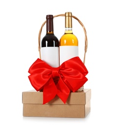 Photo of Festive basket with bottles of wine and gift box on white background