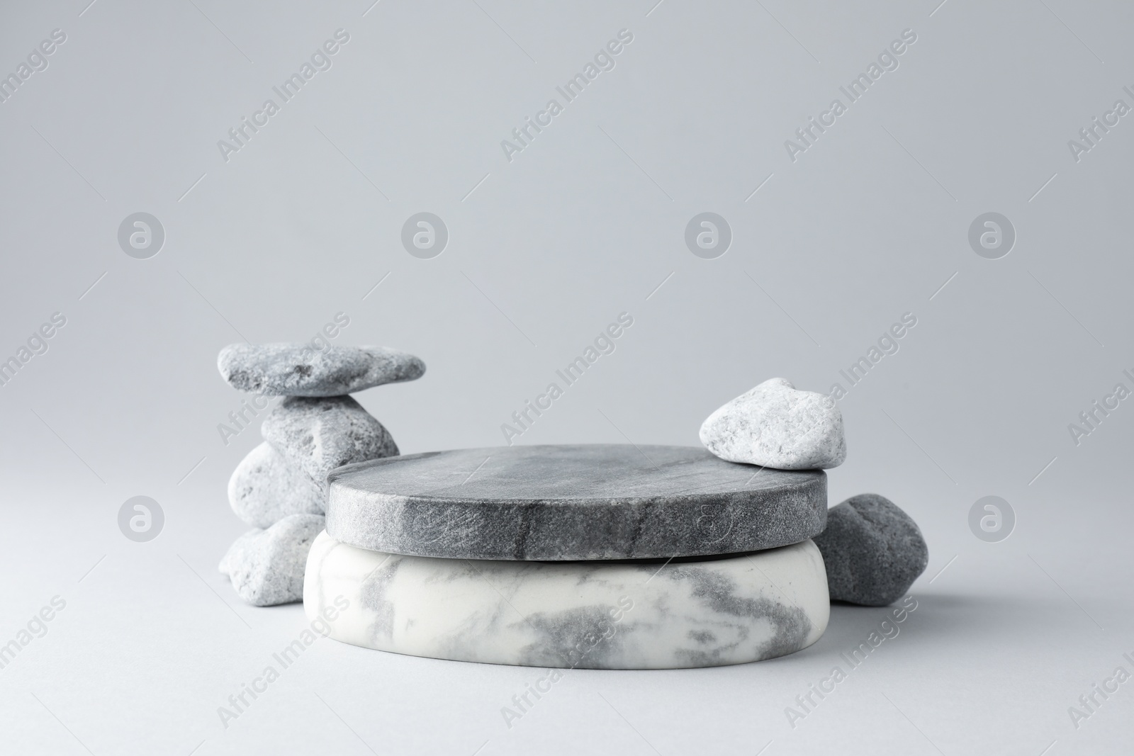 Photo of Presentation for product. Stone podium and pebbles on light grey background. Space for text