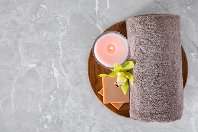 Photo of Tray with towel, candle and soap bars on grey marble table, top view. Space for text