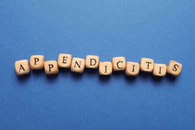 Photo of Word Appendicitis made of wooden cubes with letters on blue background, top view