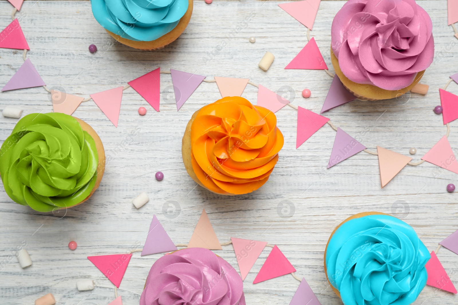 Photo of Colorful birthday cupcakes on white wooden table, flat lay