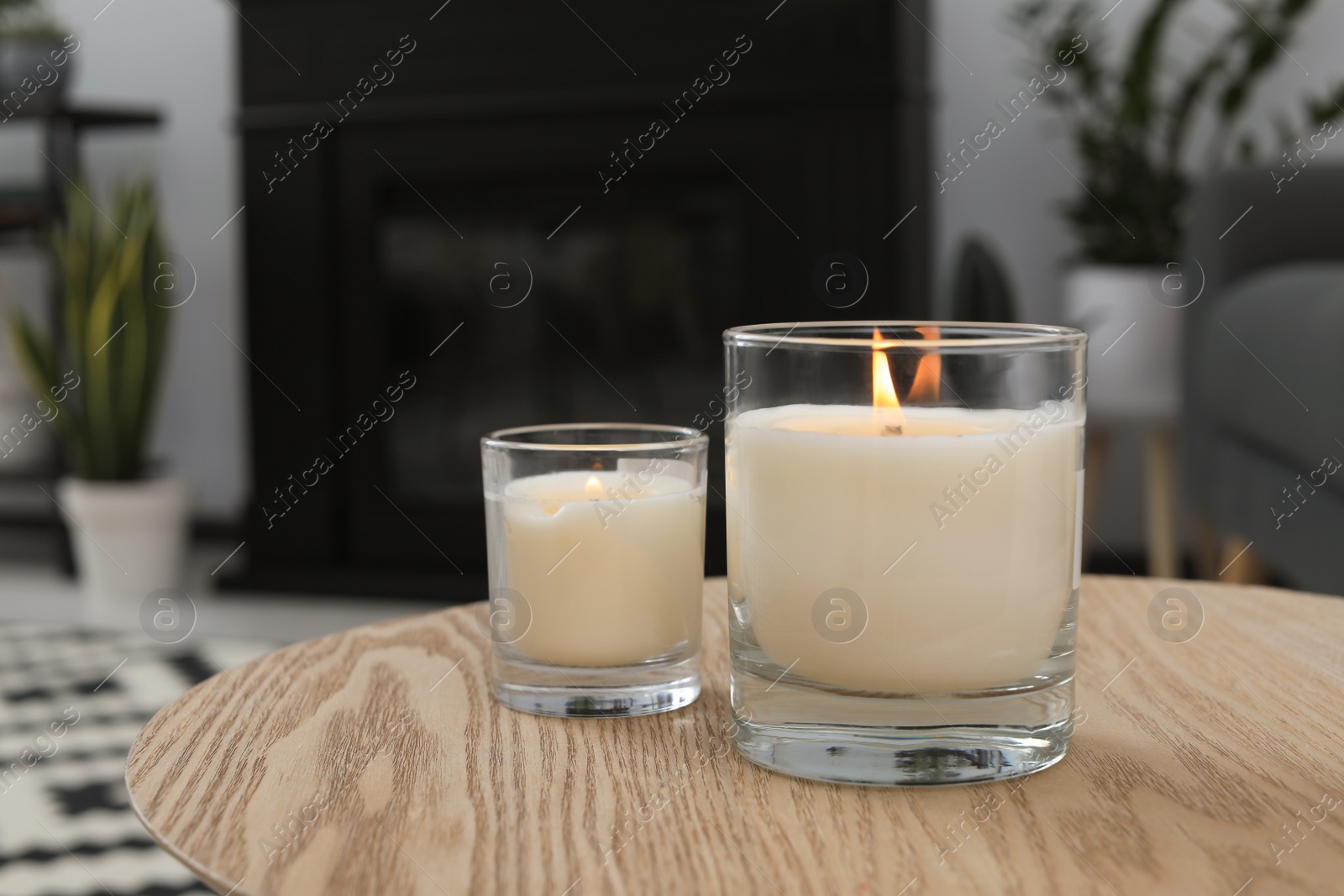 Photo of Burning candles in glass holders on wooden table indoors. Space for text