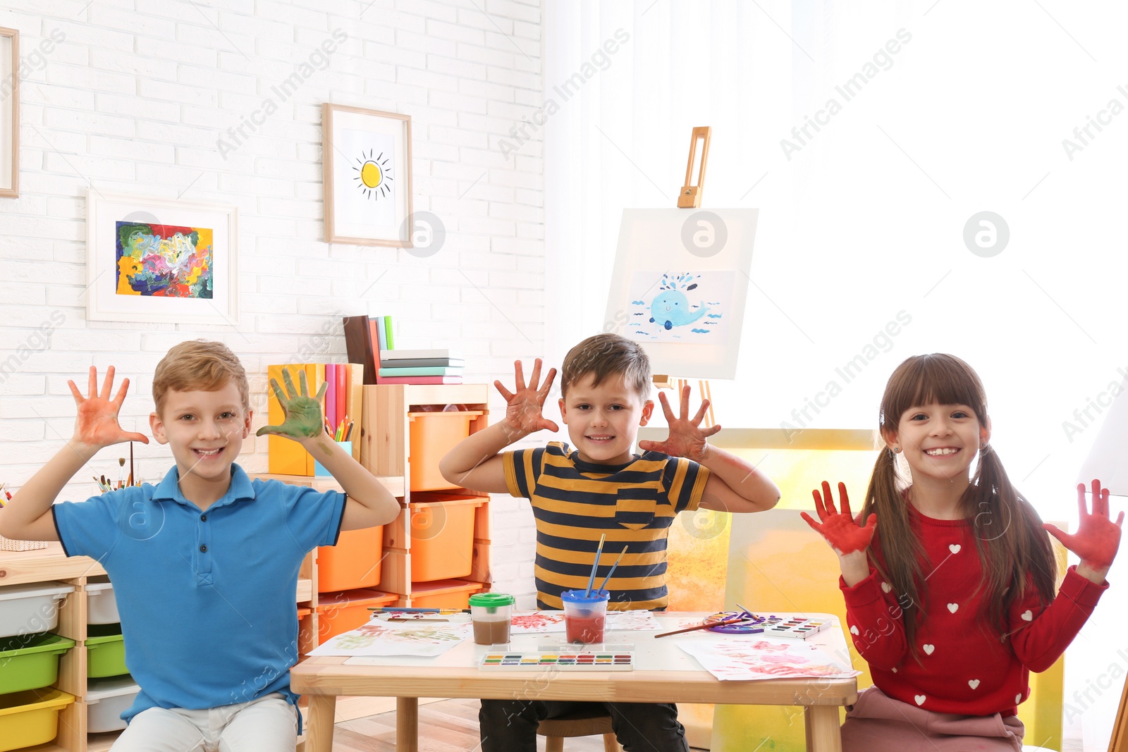 Photo of Cute little children with painted palms in room