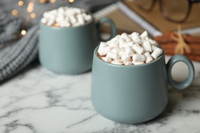 Photo of Delicious hot cocoa drink with marshmallows in cups on white marble table