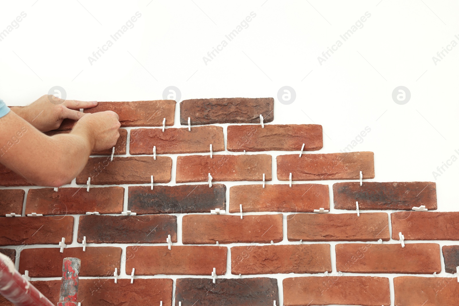 Photo of Professional builder gluing decorative brick on wall, closeup. Tiles installation process