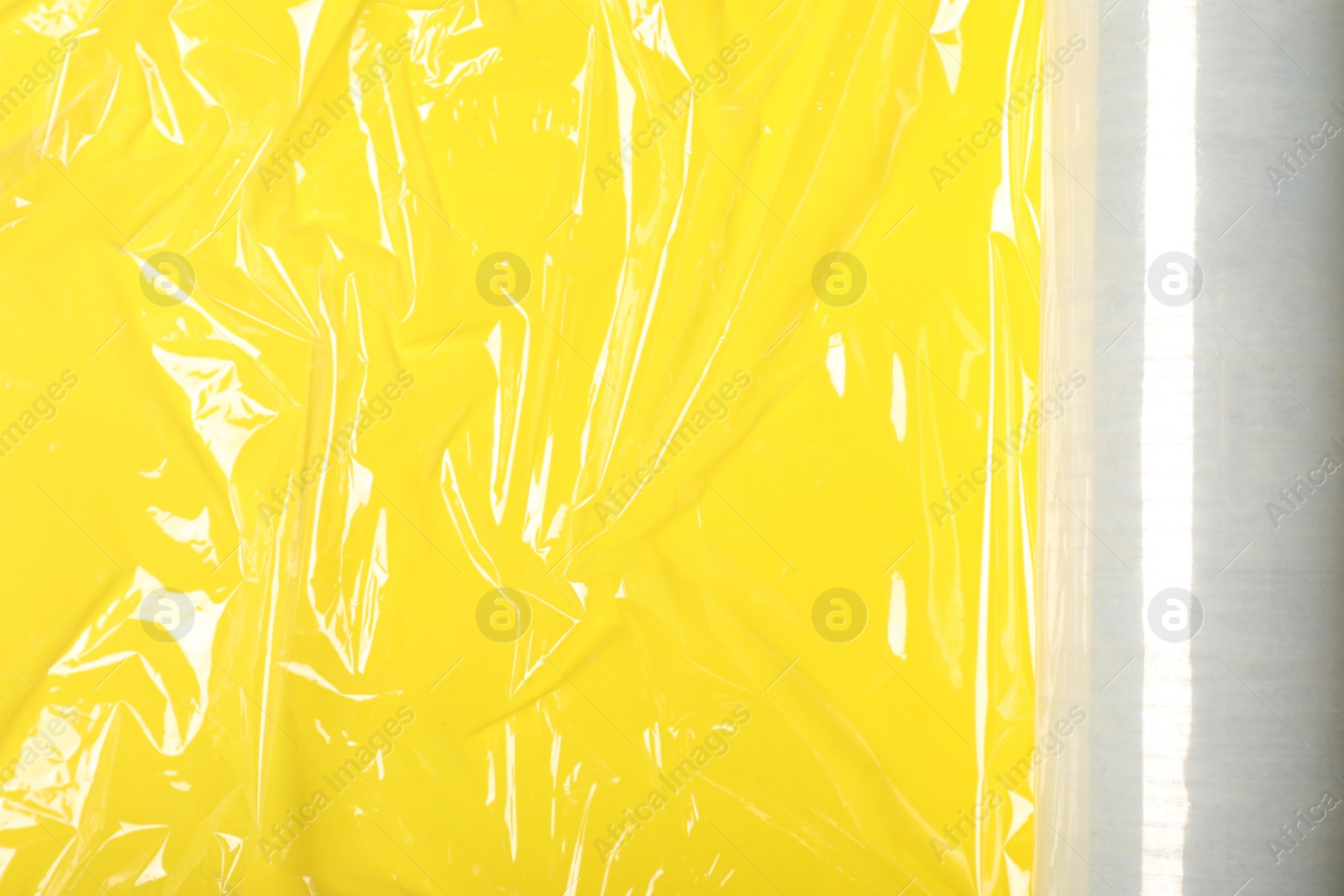 Photo of Roll of plastic stretch wrap film on yellow background, top view