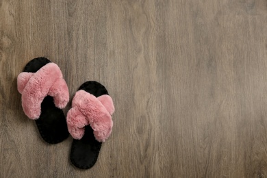 Pair of soft slippers on wooden background, flat lay. Space for text