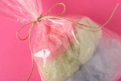 Photo of Packaged sweet cotton candy on pink background, top view