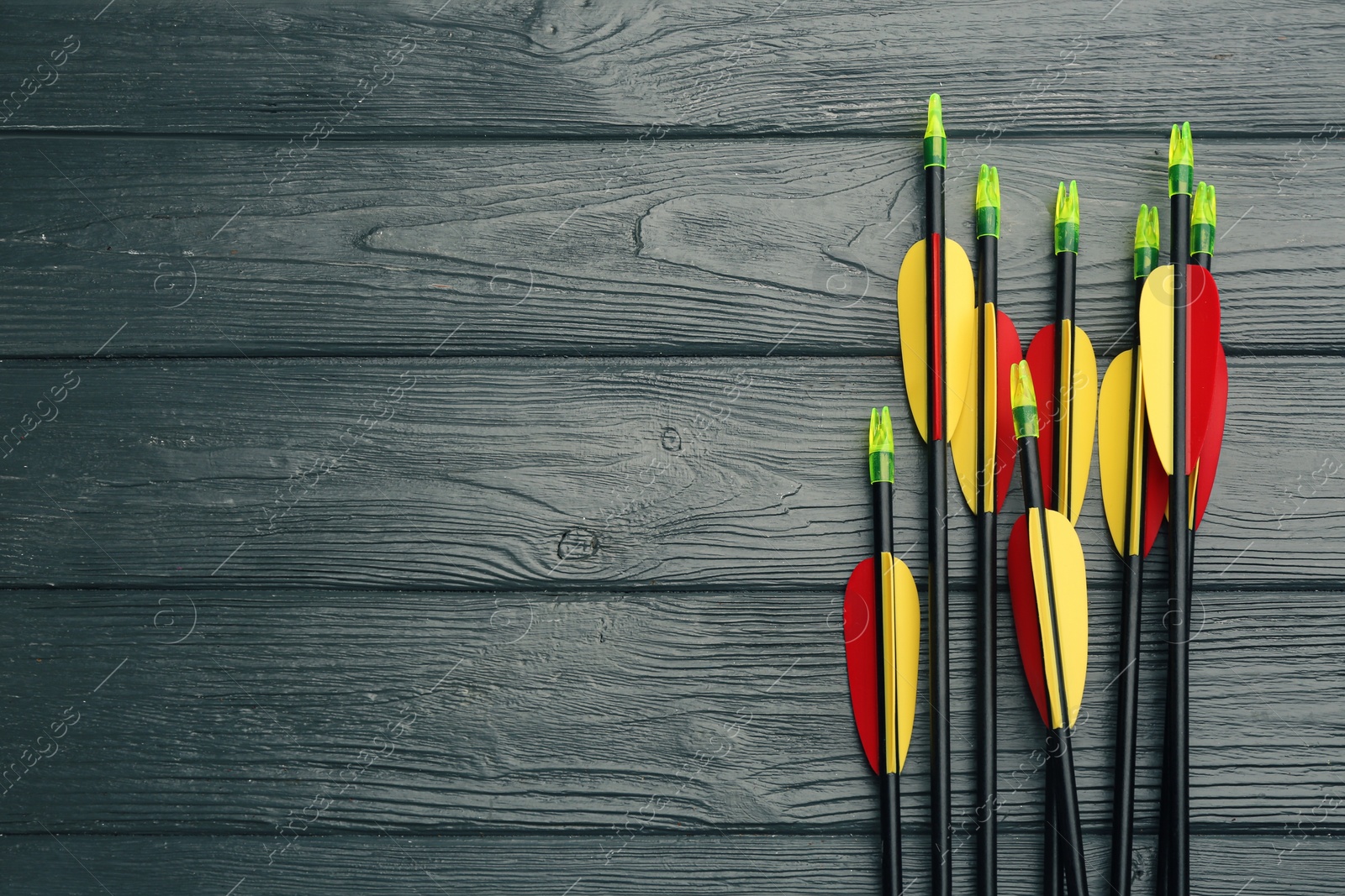 Photo of Plastic arrows and space for text on grey wooden table, flat lay. Archery sports equipment