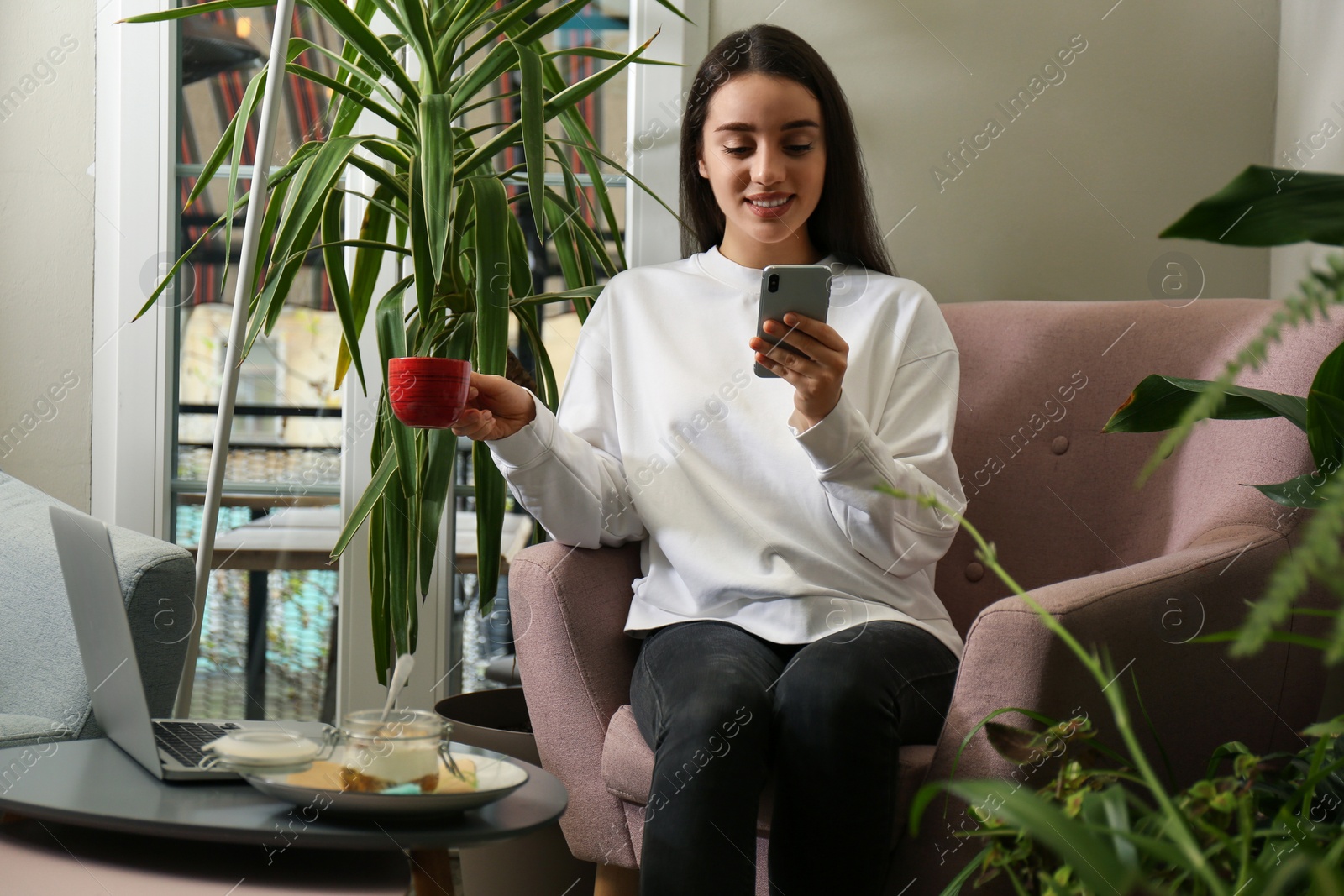 Photo of Young blogger with coffee and mobile phone in cafe