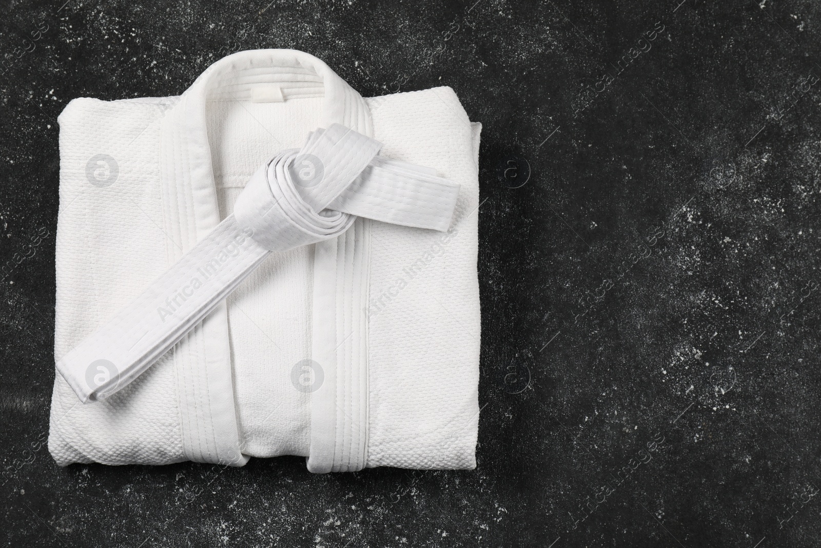 Photo of White karate belt and kimono on gray background, top view. Space for text