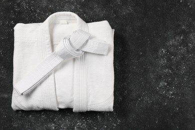 White karate belt and kimono on gray background, top view. Space for text